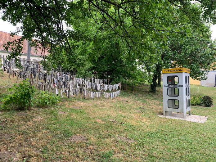 Handytelefonzelle mit Sockenskulptur im Außenbereich des Nonseums
