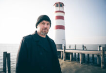 Autor Lukas Pellmann steht vor einem Leuchtturm