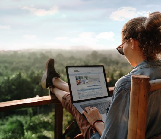 Dame sitzt mit Laptop auf einer Terrasse