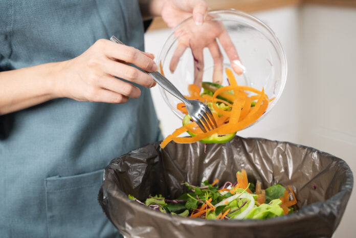 Lebensmittelreste werden vom einer Schüssel in den Mülleimer gegeben. Als Symbolbild für Lebensmittelverschwendung.