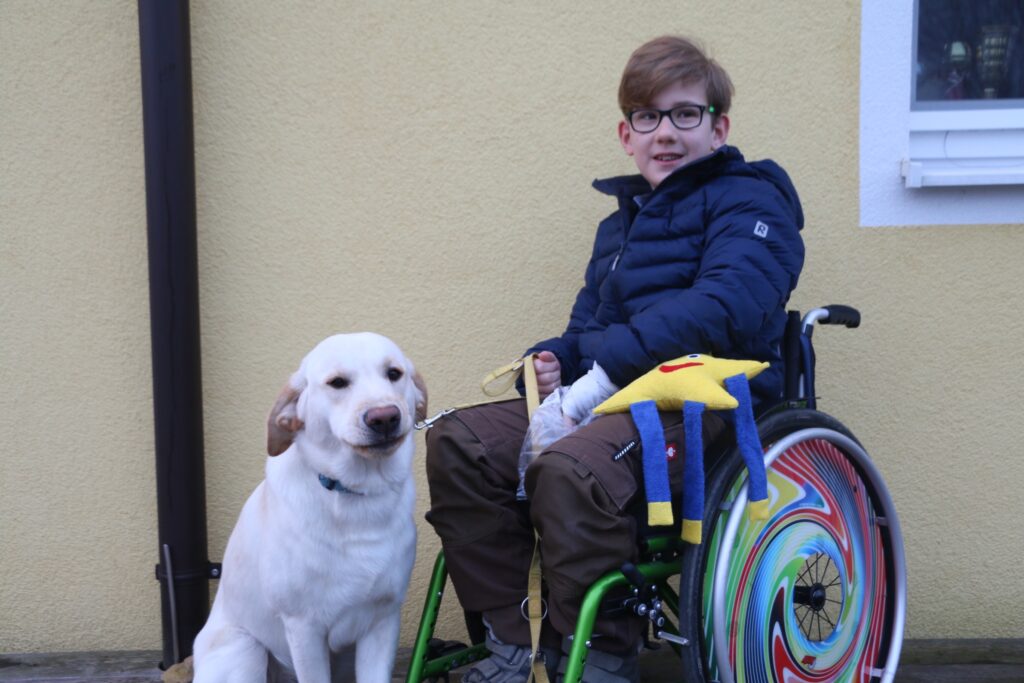 Ein Junge im Rollstuhl mit seinem Therapiehund