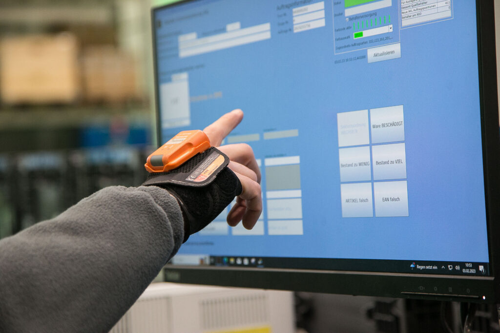 Eine Hand zeigt auf einen Bildschirm im Kleinteilelager der RWA in Traun