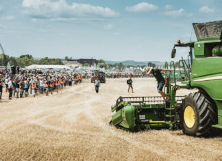 Ein großer Traktor auf einem Feld mit zahlreichen Zuschauern.