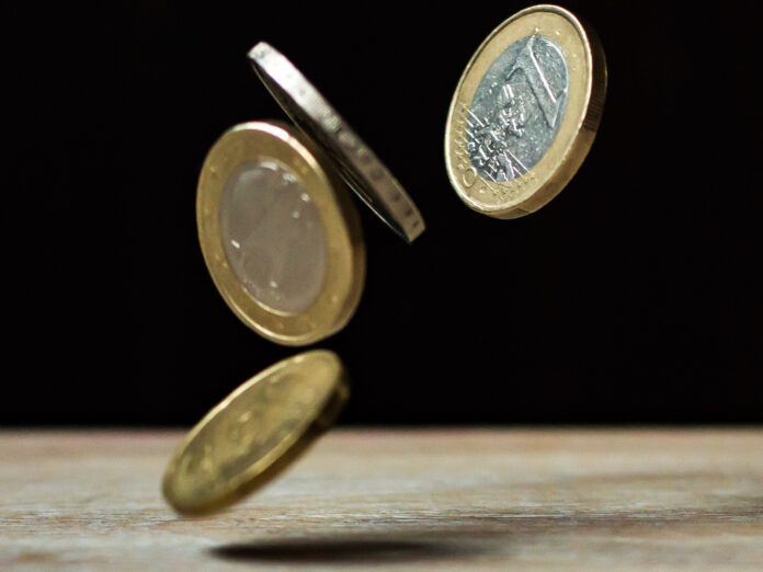 Euromünzen fallen auf einen Tisch.