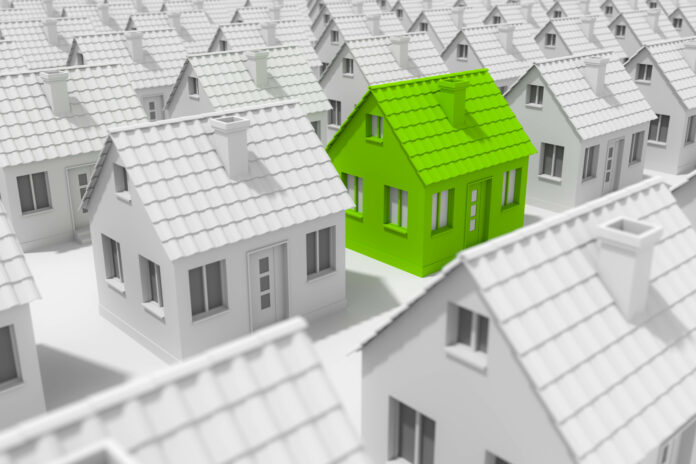 Symbolfoto für nachhaltiges Bauen; Ein grünes Haus unter vielen grauen.