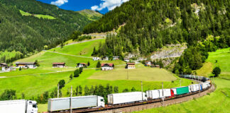 Symbolfoto für das Thema Export. LKWs auf einem Zug durch die Alpen