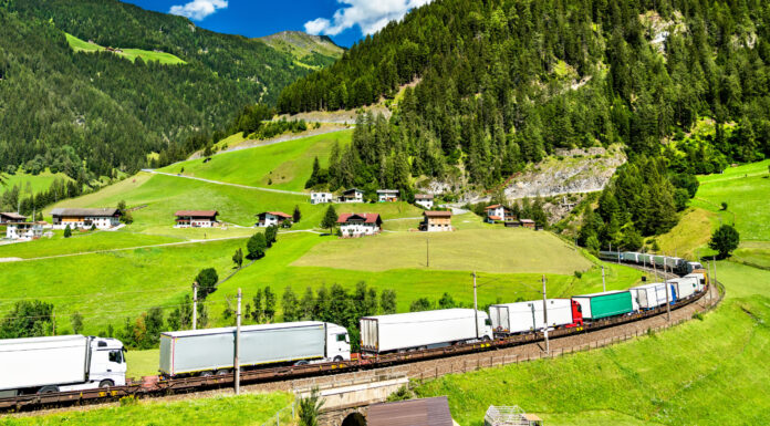 Symbolfoto für das Thema Export. LKWs auf einem Zug durch die Alpen