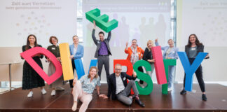 Diversität & Co-Kreation Gruppe hält große Buchstaben in die Luft DIVERSITY
