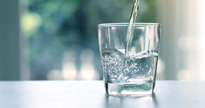 Wasser wird in ein Glas geleert