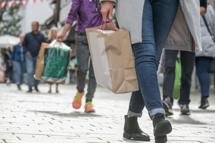 Menschen beim Shopping mit Einkaufstüten in der Innenstadt als Symbolbild für Handel