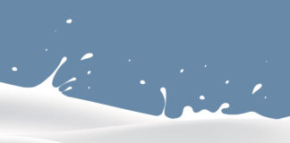 Milch schwappt vor NÖM-blauem Hintergrund