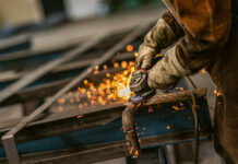 Heavy industry worker grinds steel with an angle grinder,sparks flying,close up. Symbolbild für Industrie und Wirtschaft in Osteuropa