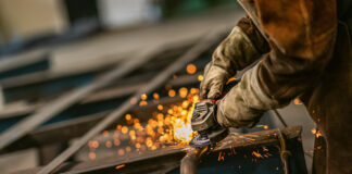 Heavy industry worker grinds steel with an angle grinder,sparks flying,close up. Symbolbild für Industrie und Wirtschaft in Osteuropa