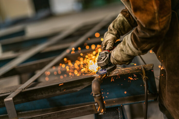 Heavy industry worker grinds steel with an angle grinder,sparks flying,close up. Symbolbild für Industrie und Wirtschaft in Osteuropa