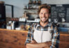 Cropped shot of a young shop owner looking happy while standing in his cafe