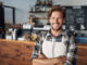 Cropped shot of a young shop owner looking happy while standing in his cafe