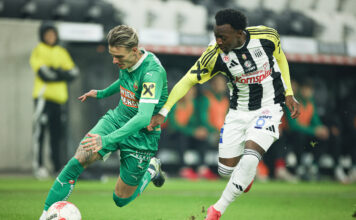 Ein Rapid-Spieler und ein LASK-Spieler am Fußballfeld. Beide mit Raiffeisen-Logo am Dress.