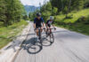 Zwei Rennradfahrer auf einer Straße durch ein Waldgebiet