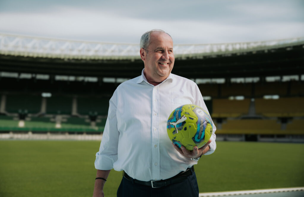 Josef Pröll hält einen Fußball im Stadion