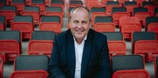 Josef Pröll sitzt in den Rängen eines Fußballstadions
