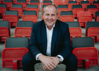 Josef Pröll sitzt in den Rängen eines Fußballstadions