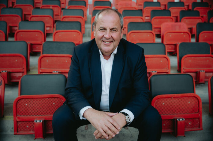 Josef Pröll sitzt in den Rängen eines Fußballstadions