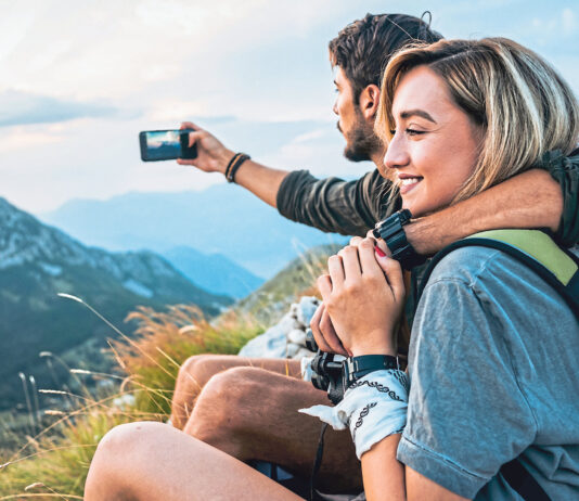 happy young couple enjoying the hike together and taking pictures