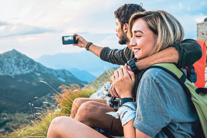 happy young couple enjoying the hike together and taking pictures
