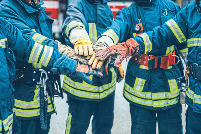 Feuerwehrmänner, die ihre Hände in der Mitte aufeinanderlegen als Symbolbild für den Raiffeisen Sozialbericht
