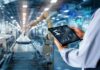 Smart industry control concept.Hands holding tablet on blurred automation machine as background