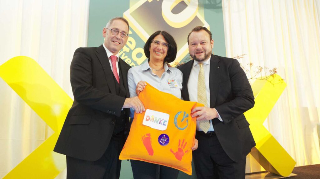 Verena Bittmann überreicht ein Geschenk vom Lichtblickhof. Das Kinderhospiz wird von der KAG unterstützt.
