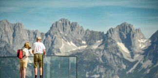 Wanderer stehen auf der Aussichtsplattform beim Starthaus vom Hahnenkamm-Rennen an der Streif in Kitzb¸hel und blicken auf die beeindruckende Berglandschaft.