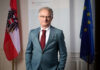 Finanzminister Markus Marterbauer stehend zwischen einer Österreich- und EU-Flagge