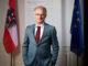 Finanzminister Markus Marterbauer stehend zwischen einer Österreich- und EU-Flagge