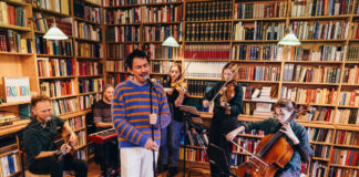 Julian le Play spielt mit Band vor einem großen Bücherregal.