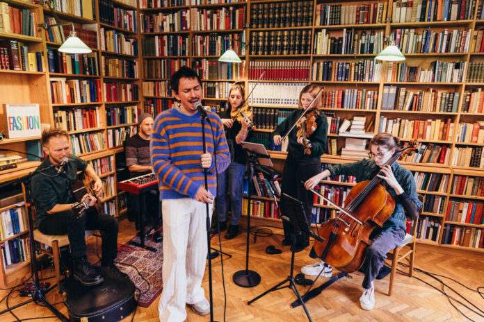 le-Play-Unplugged-08-©-Florian-Moshammer Julian le Play spielt mit Band vor einem großen Bücherregal.