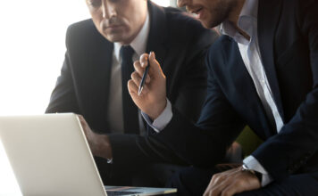 Studie: „Firmenkunden wollen echtes Sparring“ Symbolbild für Beratung: Zwei Anzugträger vor einem Laptop