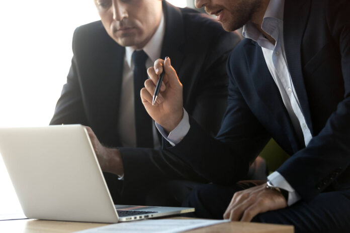Symbolbild für Beratung: Zwei Anzugträger vor einem Laptop