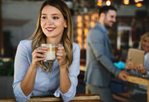 Frau in einem Café mit einer Kaffeetasse in den Händen