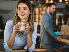 Frau in einem Café mit einer Kaffeetasse in den Händen