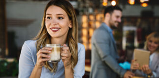 Frau in einem Café mit einer Kaffeetasse in den Händen