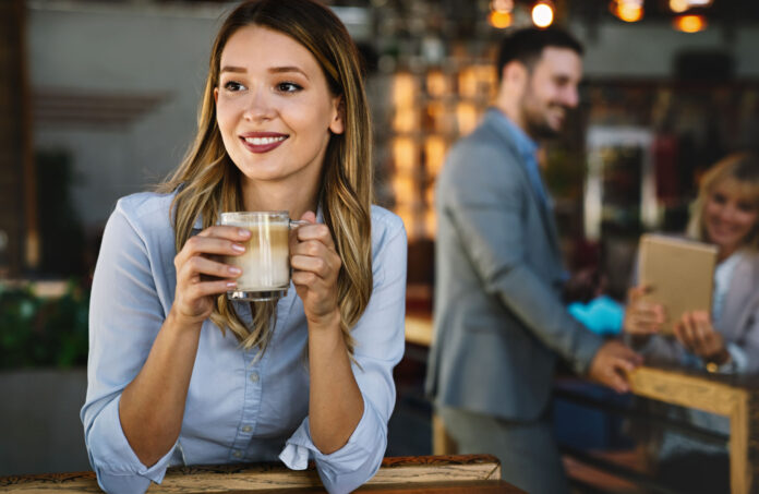Frau in einem Café mit einer Kaffeetasse in den Händen