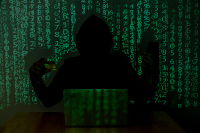 Sujetbild: Person in dunkler Kleidung mit Kapuze vor einem Laptop