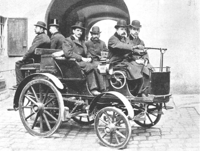 Ein Schwarz-Weiß-Foto von sechs Männern in einem Oldtimer Peugeot Type 28 Phaeton von etwa 1900.