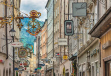 Blick in eine Einkaufsstraße mit Schildern der einzelnen Geschäften