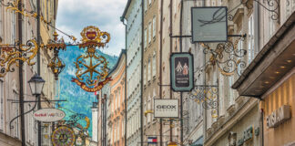 Blick in eine Einkaufsstraße mit Schildern der einzelnen Geschäften