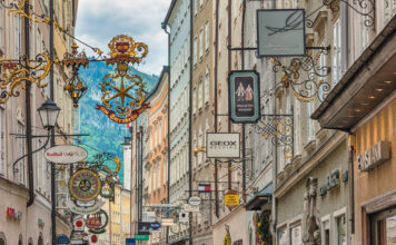 Blick in eine Einkaufsstraße mit Schildern der einzelnen Geschäften