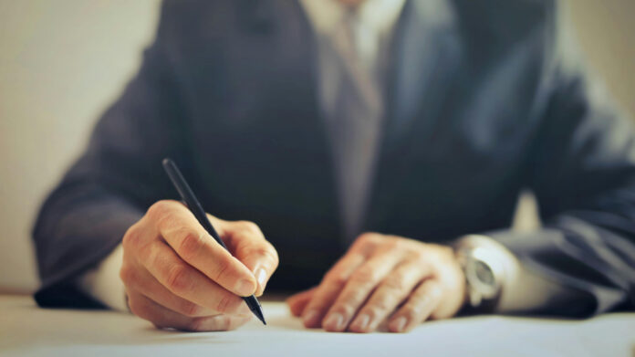 Hände mit einem Stift zur Unterschrift, Symbolbild Notar