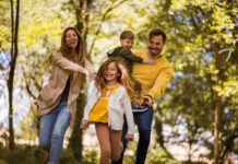 Abenteuer Osterferien: Voller Spaß, aber sicher! Happy family. Parents spending time with their children outside. Focus is on foreground.