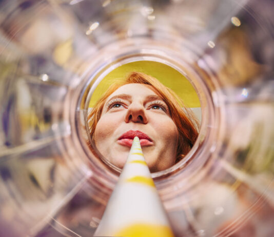 Sich aus einem leeren Glas entlang eines Strohhalms auf ein weibliches Gesicht